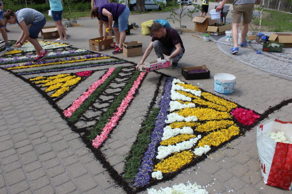 mężczyzna układa kwiaty we wzór kwiatowego dywanu